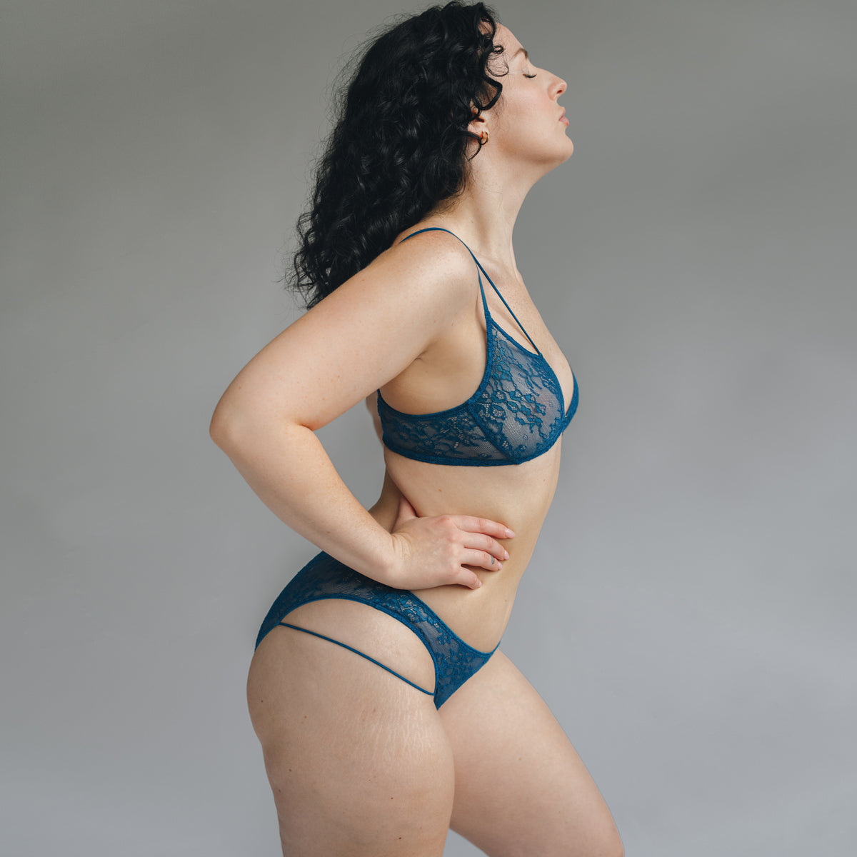 side view of a model wearing a teal blue lace bralette and bikini with double mini straps details