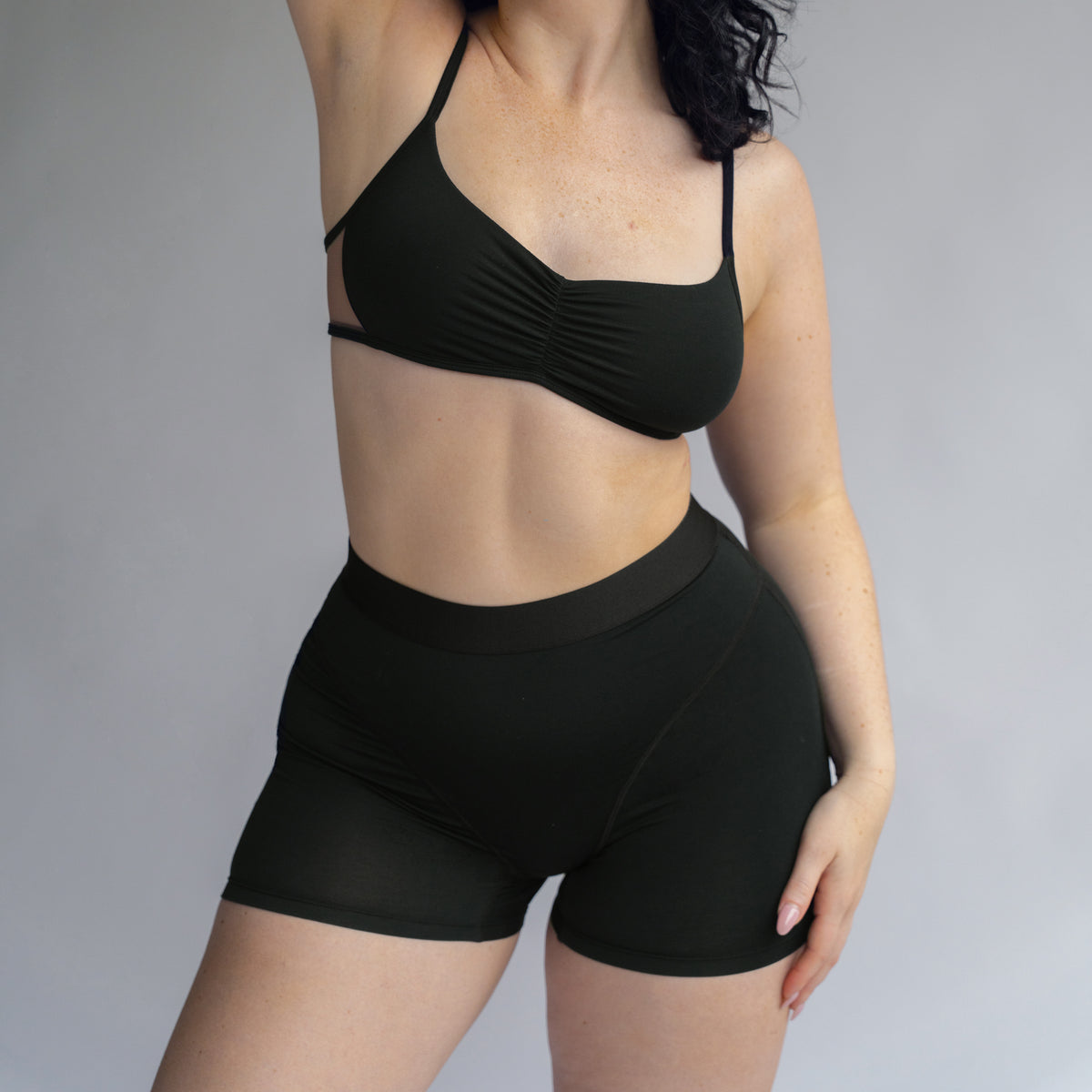 Model wearing a black bralette with center front ruching and High waisted women boxer with front seaming detail and wide waist band
